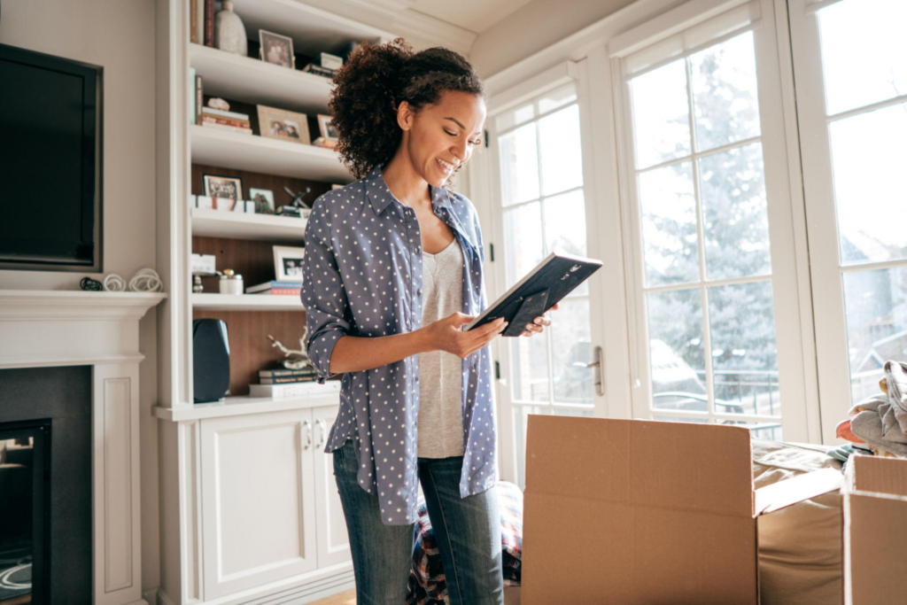 Woman organizing and unpacking household items from moving boxes during a residential home relocation.
